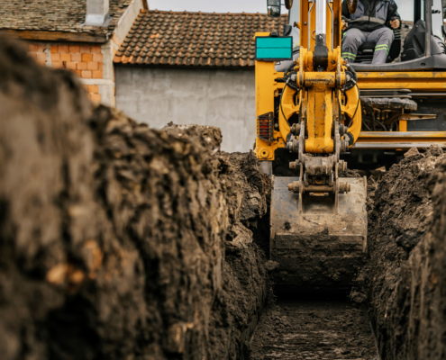 Cropped picture of a backhoe digging soil and making foundation at construction site