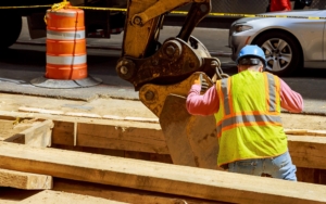 Back view of an excavator digging into city streets