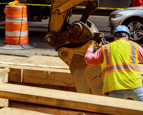 Back view of an excavator digging into city streets