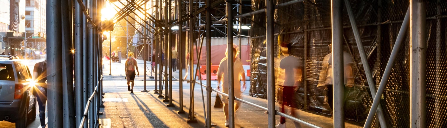 Side view of people walking under construction scaffolding in New York City