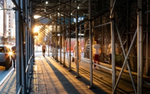 Side view of people walking under construction scaffolding in New York City