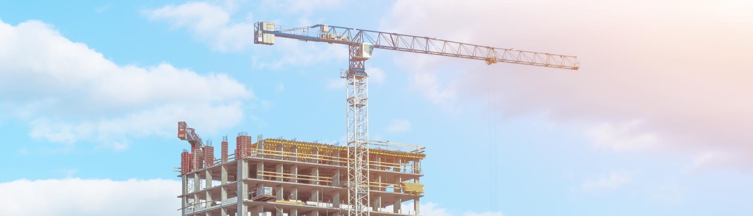 Side view of a crane with a partly cloudy sky in the background